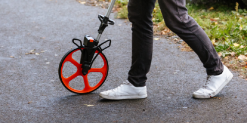 Detailaufnahme von den Beinen einer Person in Jeans und roten Sneakern, die in einer Gruppe an einem Bordstein steht. Detailaufnahme von den Beinen einer Person in Jeans und roten Sneakern, die in einer Gruppe an einem Bordstein steht.