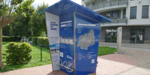 Solarbetriebene Ladestation ist ein zwei Meter großer, blauer Kasten mit Fahrradbügeln Solarbetriebene Ladestation ist ein zwei Meter großer, blauer Kasten mit Fahrradbügeln