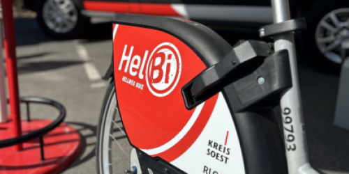 Rückrad eines Fahrrads steht vor einem weiß-roten Buli, der als InfoMobil beschriftet ist. Rückrad eines Fahrrads steht vor einem weiß-roten Buli, der als InfoMobil beschriftet ist.